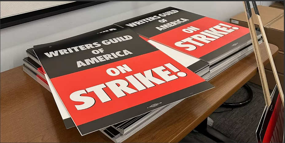 A stack of signs labelled "Writers Guild of America Strike" on a table.