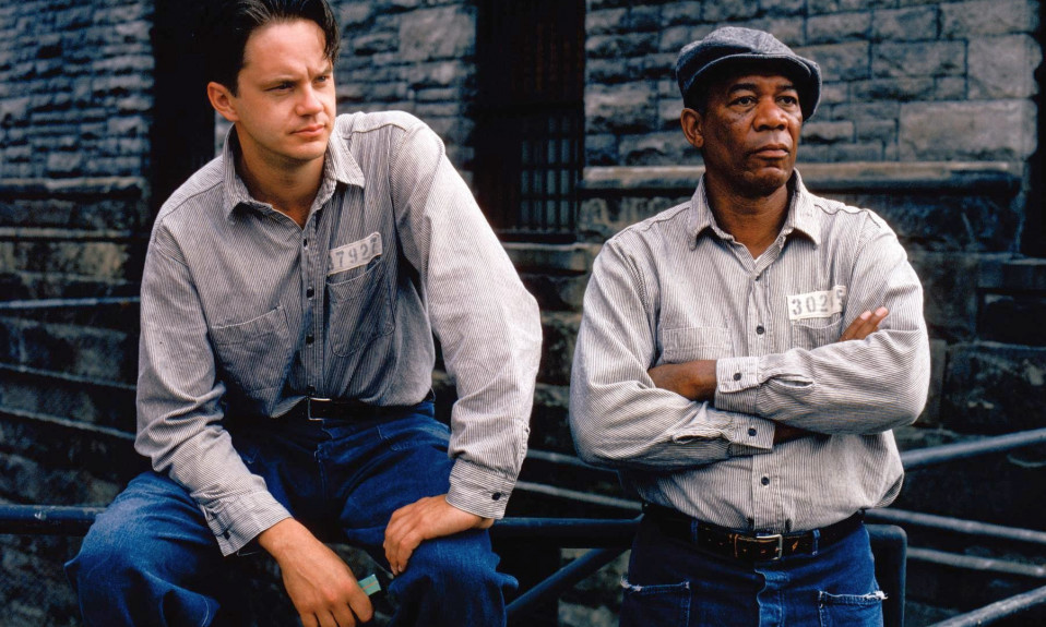 A white man and a black man side by side in 90s-style prison uniforms,