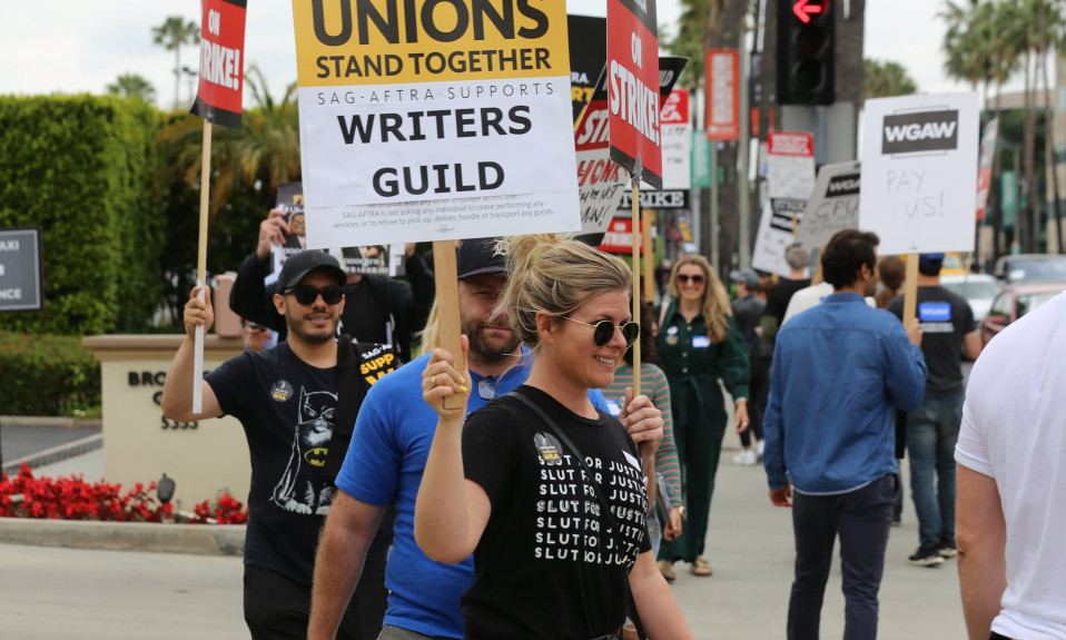 A SAG-AFTRA union member joins a WGA strike in solidarity.